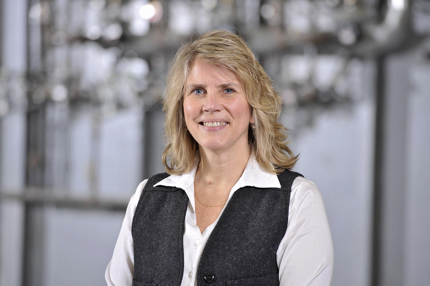 Headshot for Joy Milne, a woman with blond hair down to her shoulders who is wearing a white blouse with a black vest.